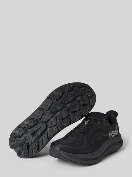 Produktfoto, sneakersy z zaokrąglonym czubkiem i wiązaniem, model 'KAWANA 3' od HOKA, detal z logo, wysokość obcasa 4 cm, wysokość cholewki 7 cm, szerokość w rozmiarze 44: 9 cm, kolor czarny, faktura matowa