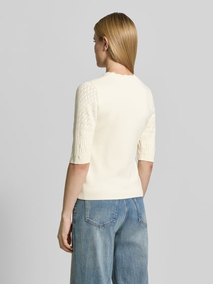 Frauenmodel trägt Strickpullover mit 1/2-Arm Modell 'MILOS' von Vila, cremefarben, Viskose-Mix, Regular-Fit, Rundhalsausschnitt, Rückenlänge 52 cm, Ärmellänge 32 cm, Strukturmix am Arm, Ganzkörperansicht Rückansicht.