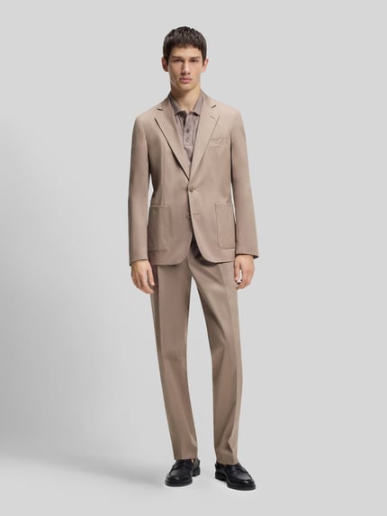 Męski model nosi Slim Fit Sakko aus Baumwoll-Mix Modell 'HANFRED262X' von HUGO, jednokolorowy, kołnierz z połami, marynarka na 2 guziki, brustasza, nakładane boczne kieszenie, mieszanka bawełny, Ganzkörperansicht von vorne.