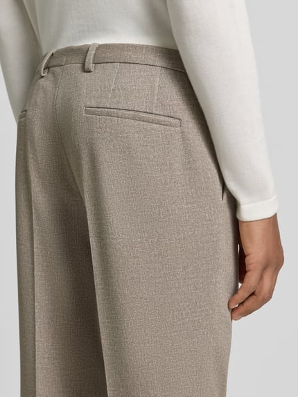 Männermodel trägt Super Slim Fit Anzughose mit Viskose-Anteil Modell 'Hesten263X-H' von HUGO in Beige mit feiner Struktur, Detailaufnahme, Herren Anzughose von HUGO.