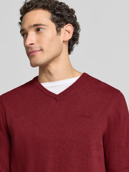 Männermodel trägt Pullover mit Logo-Detail von S.OLIVER CASUAL in Unifarben, V-Ausschnitt, Feinstrick, Nahaufnahme Oberkörper.