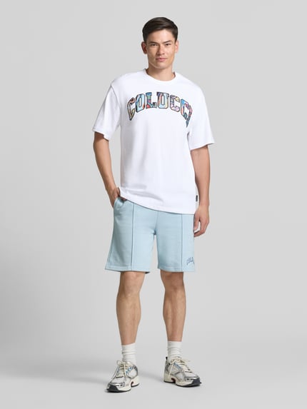 Männermodel trägt T-shirt met 1/2-mouwen van COLUCCI in wit, puur katoen, recht model, ronde hals, ruglengte maat M 72 cm, voorkant ganzekörperaanzicht.