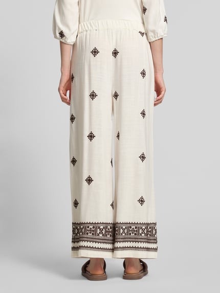 Frauenmodel trägt Hose aus Viskose-Leinen-Mix mit Stitchings von Christian Berg Woman Selection in Creme mit braunen Details, Ganzkörperansicht Rückansicht.