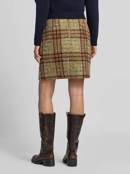 Frauenmodel trägt Minirock im Allover-Look mit Reißverschluss von Christian Berg Woman, Karomuster in Grün und Braun, Material-Mix mit Baumwoll-Anteil, gerader Schnitt, Rückansicht Ganzkörperansicht.