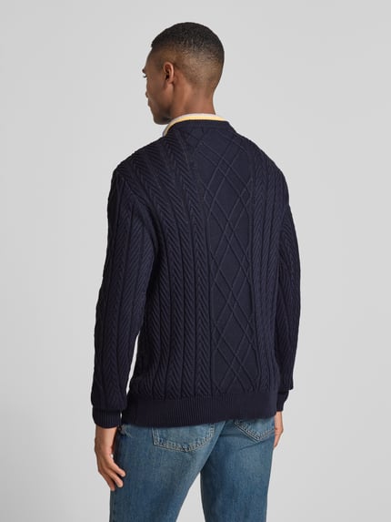 Männermodel trägt Strickpullover aus Baumwoll-Modal-Mix von Guess in Dunkelblau, Zopfmuster, Regular Fit, Rückenansicht, Ganzkörperansicht Rückansicht.