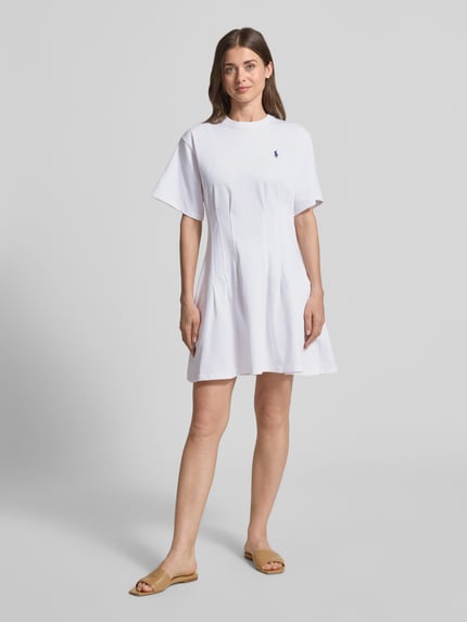 Frauenmodel trägt Leicht ausgestelltes Sweatkleid aus reiner Baumwolle von Polo Ralph Lauren in Weiß, Melange-Optik, Mini-Länge, Logo-Stitching, Kurzarm, gelegte Falten, Sweat, Ganzkörperansicht von vorne.