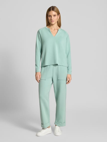 Frauenmodel trägt Sweatpants mit Eingrifftaschen und Aufschlag von Christian Berg Woman im Material-Mix mit Modal-Mix, Relaxed-Fit, hellgrün, glatte Textur, Ganzkörperansicht von vorne.