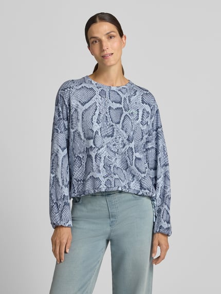 Frauenmodel trägt Oversized Sweatshirt aus Baumwoll-Mix von Marc Cain, blau-graues Schlangenprint-Design, Ballonärmel, Nahaufnahme Oberkörper. Damen Sweatshirt, Rundhalsausschnitt, elastische Abschlüsse, Baumwoll-Mix.