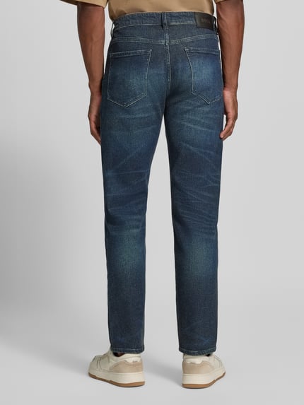 Männermodel trägt Straight Fit Jeans aus Baumwoll-Mix Modell 'C-Ogden' von BOSS in dunklem Blau mit deutlicher Waschung, Ganzkörperansicht Rückansicht. Herren Straight Fit Jeans von BOSS.