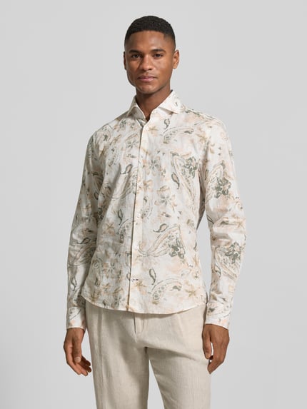 Männermodel trägt Slim Fit Business-Hemd aus Leinen-Mix Modell 'Pai' von JOOP! Collection mit Paisley-Muster, Beige- und Grüntöne, Ganzkörperansicht von vorne.