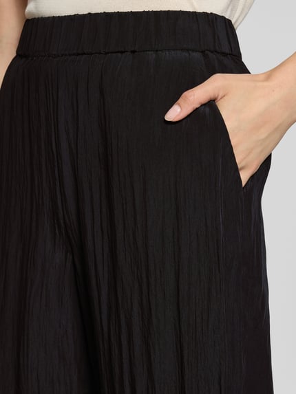 Frauenmodel trägt Stoffhose aus Viskose-Mix Modell 'Cevil' von someday, schwarze Farbe, lockere Passform, Nahaufnahme Oberkörper.