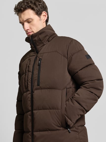 Männermodel trägt Steppjacke mit vielen Reißverschlusstaschen von s.Oliver RED LABEL, unifarben, strukturierte Webware, Nahaufnahme Oberkörper.