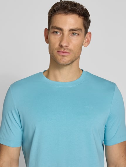Männermodel trägt Regular Fit T-Shirt aus reiner Baumwolle von s.Oliver RED LABEL in Optik: Unifarben, Label-Print, Nahaufnahme Oberkörper.