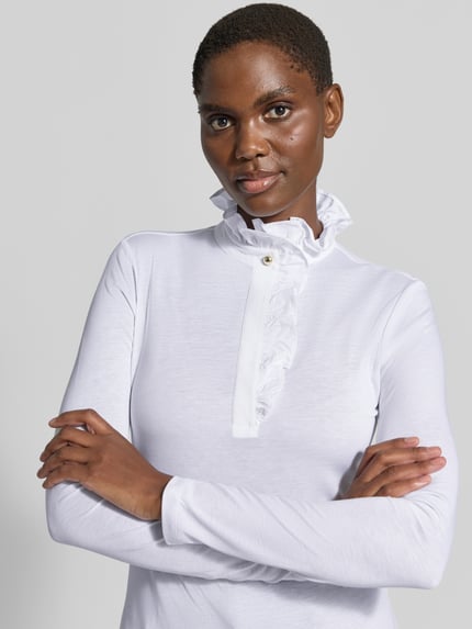 Frauenmodel trägt Longsleeve mit Rüschen von Rich & Royal aus Lyocell-Baumwoll-Mix in Weiß, taillierter Schnitt, Nahaufnahme Oberkörper.