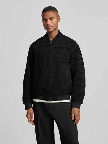 Männermodel trägt Bomberjacke mit Reißverschluss von ARMANI EXCHANGE, Material-Mix mit Stretch-Anteil, Regular-Fit, Schwarz, Ganzkörperansicht von vorne.