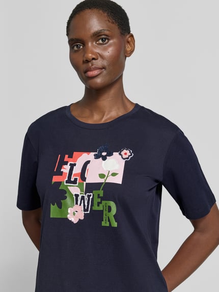 Vrouwenmodel draagt Regular Fit T-Shirt uit puur katoen van Marc Cain met bloemenstitching en ronde hals, ruglengte maat 36: 57 cm, Nahaufnahme Oberkörper.