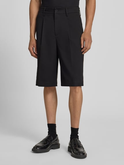 Männermodel trägt schwarze Loose Fit Chinoshorts mit Viskose-Anteil von Only & Sons, glatte Struktur, Herren, Nahaufnahme Oberschenkel.