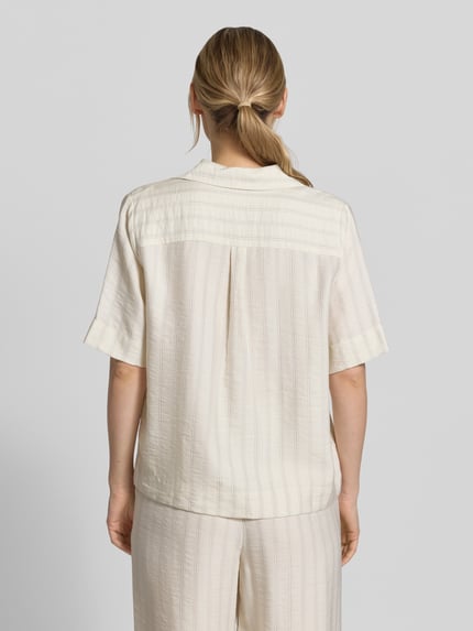 Frauenmodel trägt Regular Fit Hemdbluse aus Lyocell-Mix Modell 'MARIE' von Selected Femme mit Optik:Allover-Muster, Nadelstreifen, Rückenpasse mit Raffung, Johnny-Kragen, V-Ausschnitt, verdeckter Knopfleiste, Kurzarm, Ganzkörperansicht Rückansicht.