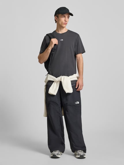 Männermodel trägt T-Shirt mit Logo-Stitching von The North Face in Schwarz, reine Baumwolle, gerader Schnitt, Ganzkörperansicht von vorne.