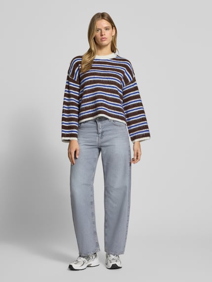 Frauenmodel trägt Pullover aus Schurwolle mit Rundhalsausschnitt von PIECES, mehrfarbig gestreifte Strickoptik, Ganzkörperansicht von vorne.
