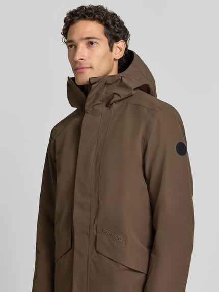 Männermodel trägt Regular Fit Parka mit Kapuze Modell 'Kenny' von Didriksons in Braun, glatte Textur, Nahaufnahme Oberkörper. Herren Parka mit Eingrifftaschen, Rückenlänge 99 cm, Schulterbreite 48 cm, Brustweite 59 cm, Ärmellänge 72 cm.