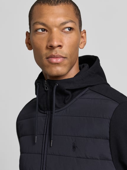 Männermodel trägt Regular Fit Strickjacke aus Baumwoll-Mix von Polo Ralph Lauren in Schwarz mit glatter Textur, Nahaufnahme Oberkörper. Herren Strickjacke von Polo Ralph Lauren