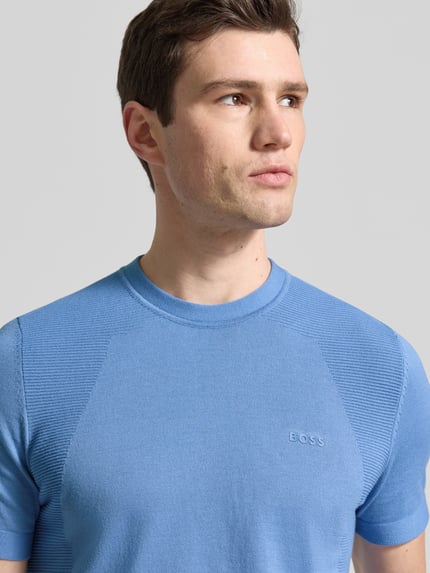 Männermodel trägt Regular Fit T-Shirt aus Baumwoll-Mix Modell 'MOMENTUM-LITE' von BOSS Green in Optik: Unifarben mit Label-Print, Rundhals, Ärmelform: Kurzarm, Material: Baumwoll-Mix, Nahaufnahme Oberkörper.