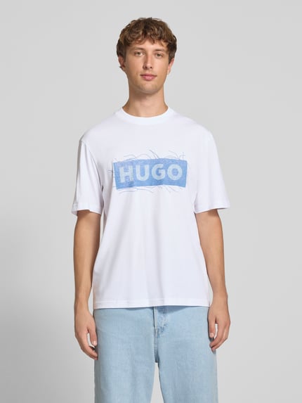 Męski model nosi biały t-shirt Regular Fit T-Shirt aus reiner Baumwolle Modell 'Naxter' von HUGO, gładka faktura, jasnoniebieski nadruk, Męski t-shirt od HUGO Blue, Ganzkörperansicht von vorne.