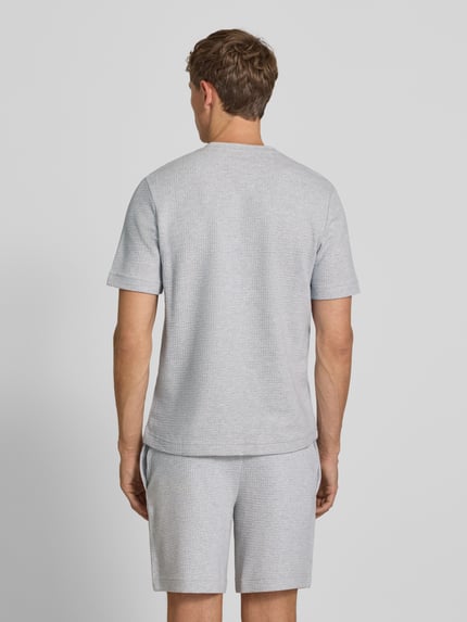 Männermodel trägt Herren T-Shirt aus Baumwoll-Mix Modell 'AUSTIN' von HUGO in Hellgrau mit feiner Struktur, Ganzkörperansicht Rückansicht.
