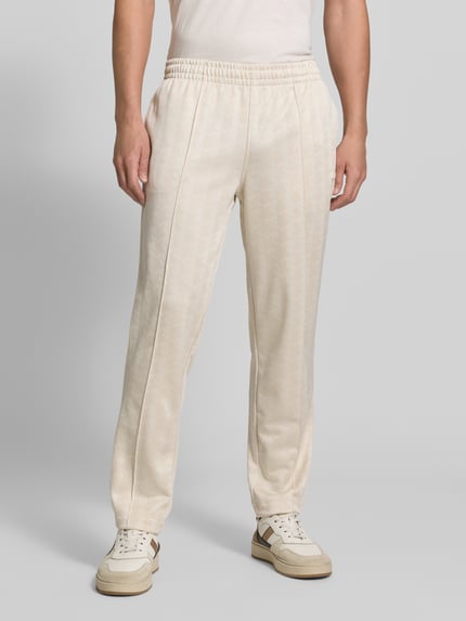 Männermodel trägt cremefarbene Regular Fit Sweathose aus Baumwoll-Mix von Lacoste, dezentes Muster, bequemer Stoff, Ganzkörperansicht von vorne. Herren Sweathose von Lacoste
