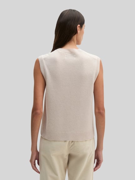 Vrouwenmodel draagt Regular Fit Strickweste aus reiner Schurwolle van Marc O'Polo in lichtbeige, grof gebreide textuur, volledig van achteren