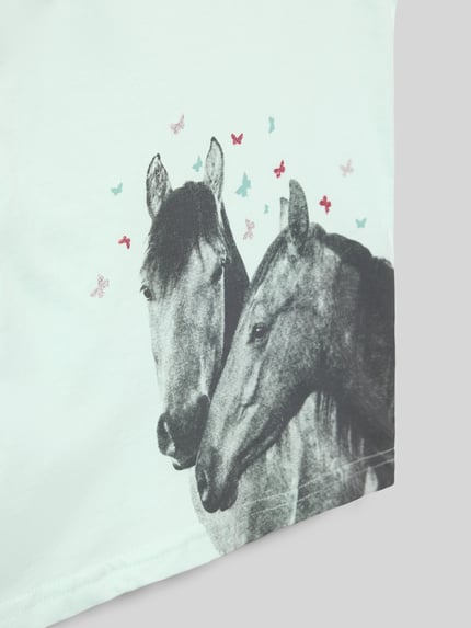 Mädchen trägt T-Shirt mit Motiv-Print und Rundhalsausschnitt von Blue Seven, Reine Baumwolle, Regular-Fit, Nahaufnahme Oberkörper.