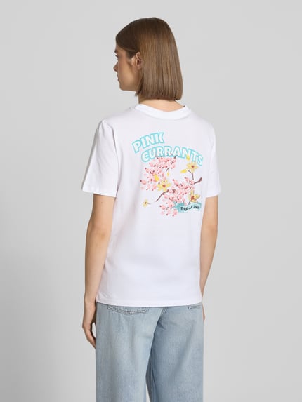 Modelka prezentuje damski t-shirt Regular Fit T-Shirt aus reiner Baumwolle Modell 'BRIANNA' von Pieces, efekt: jednolity kolor, nadruk z motywem, okrągły dekolt, krótki rękaw, dżersej, czysta bawełna, widok całej sylwetki od tyłu.