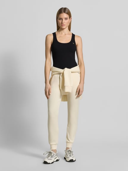 Kobiece modelka nosi Slim Fit Top aus Viskose-Mix Modell 'Colette' od Guess Activewear, czarny, gładka tekstura, logo, krój slim fit, okrągły dekolt, długość tyłu w rozmiarze S: 51 cm, całkowity widok z przodu.
