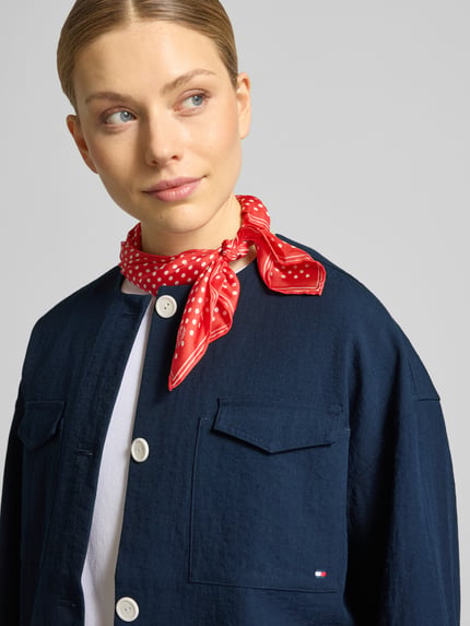 Kobiece model nosi Boxy Fit Kurzblazer aus Viskose-Mix od Tommy Hilfiger, efekt: jednolity kolor, pudełkowy krój, okrągły dekolt, długość krótka, wyhaftowane logo, listwa guzikowa, długi rękaw, mankiet, kieszenie z patką na piersi, mieszanka wiskozy, z przodu zbliżenie górnej części ciała.