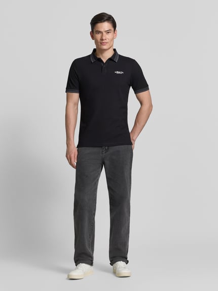 Męski model nosi Regular Fit Poloshirt aus Baumwoll-Mix od s.Oliver RED LABEL, gładki czarny, bawełniany piqué, krótki rękaw, widok całej sylwetki z przodu.