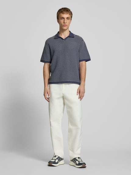 Männermodel trägt Regular Fit Poloshirt mit V-Ausschnitt von Jack & Jones aus reiner Baumwolle, Strickshirt, Ganzkörperansicht von vorne.