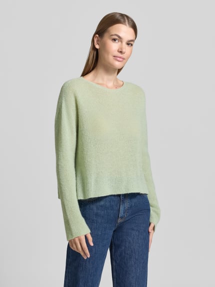 Vrouwenmodel draagt Oversized Wollpullover aus Alpaka-Mix van DRYKORN in lichtgroen, riblook, ronde hals, ruglengte maat S 48 cm, mouwlengte 70 cm, oversized fit, mix van alpaca en wol, dames wollpullover, ganzlichaamsaanzicht van voren.