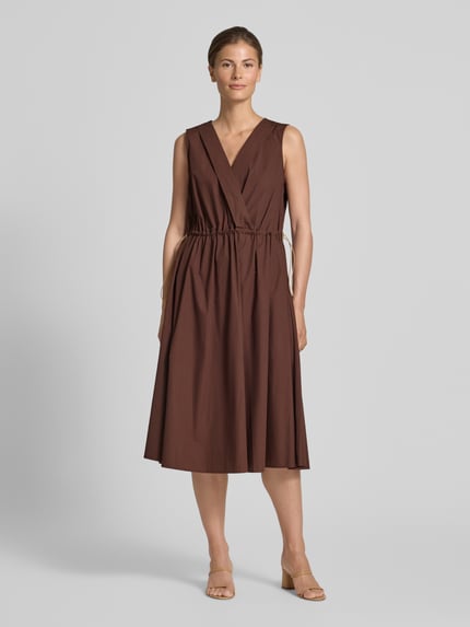 Frauenmodel trägt knielanges Cocktailkleid mit Kordelzug und Kordelstoppern von Rinascimento in Braun, reine Baumwolle, V-Ausschnitt, taillierter Schnitt, glatte Struktur, Ganzkörperansicht von vorne.