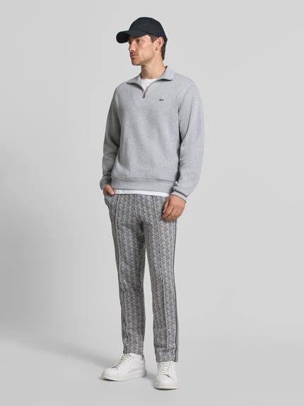 Männermodel trägt Regular Fit Sweathose mit Baumwoll-Anteil von Lacoste in Grau mit geometrischem Muster, Ganzkörperansicht von vorne. Herren Sweathose von Lacoste