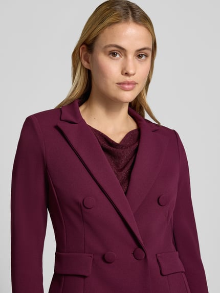 Vrouwenmodel draagt Slim Fit Blazer met Reverskraag van Rinascimento in elastische materiaalmix met dubbele knoopsluiting en klepzakken, kleur bordeaux, ruglengte maat S 53 cm, nahaufnahme bovenlichaam.