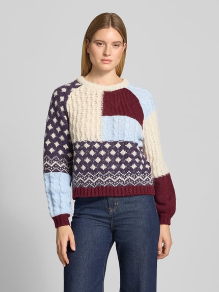 Frauenmodel trägt Pullover mit Ballonärmeln Modell 'VMKRISTIN' von VERO MODA, mehrfarbig, Patchwork-Strick, Ganzkörperansicht von vorne.