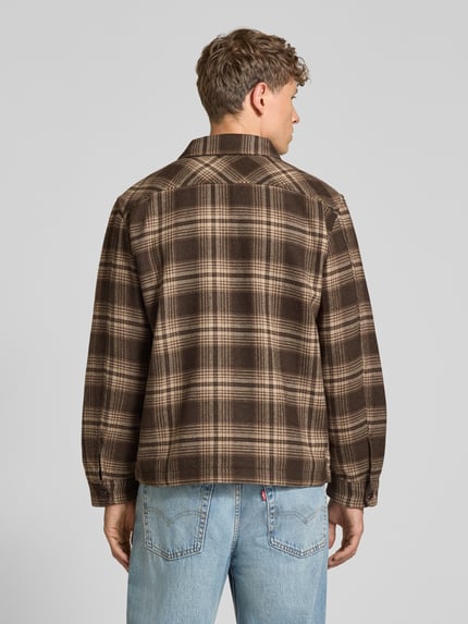 Männermodel trägt Freizeithemd mit durchgehender Knopfleiste von Selected Homme, kariertes Allover-Muster in Braun, Rückansicht Ganzkörperansicht.