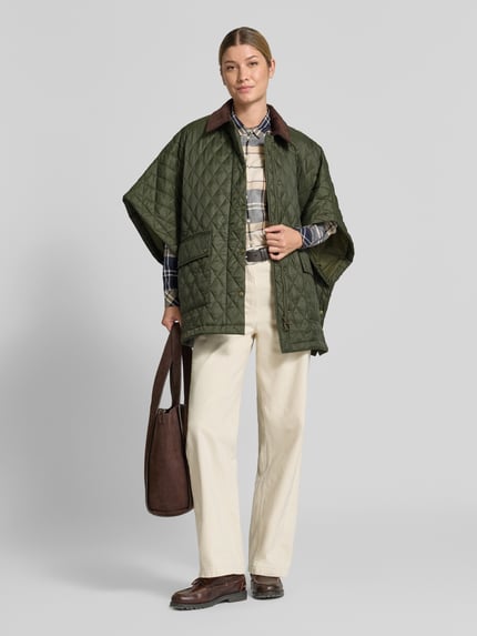 Frauenmodel trägt Oversized Poncho mit Umlegekragen Modell 'MILDRED QUILTED CAPE' von Barbour in Olivgrün mit Karomuster, Damen Poncho, Ganzkörperansicht von vorne.