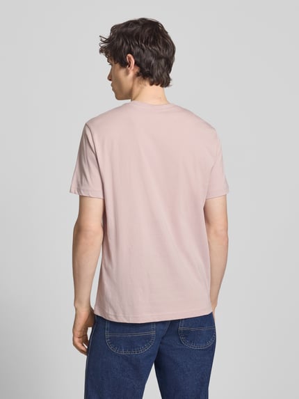 Männermodel trägt T-shirt mit labelstitchings en ronde hals van CHAMPION van puur katoen, regular fit, ruglengte bij maat M 66 cm, geheel in lichtroze tint, gladde stof; Ganzkörperansicht Rückansicht.