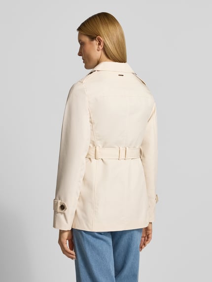 Vrouwenmodel draagt Regular Fit Trenchcoat uit katoenmix van s.Oliver RED LABEL, effen kleuren, twill, labelapplicatie, waterafstotend, achterpas, schoudertrensjes, lange mouwen, kort, tailleriem, steekzakken, eenrijige knoopsluiting, cropped lengte, achteraanzicht hele lichaam
