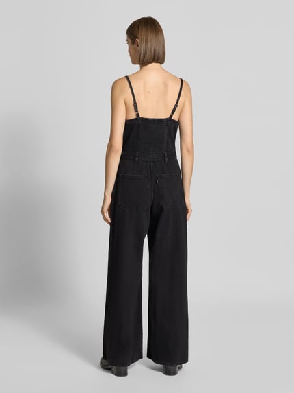 Frauenmodel trägt Regular Fit Jumpsuit aus reiner Baumwolle Modell 'SEAMED' von Levi's® 300 in Schwarz, breite Hosenbeine, Ganzkörperansicht Rückansicht.