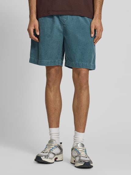 Männermodel trägt Jeansshorts mit elastischem Bund Modell 'Reynold' von Carhartt Work In Progress in Blau, Reine Baumwolle, Relaxed-Fit, Ganzkörperansicht von vorne.
