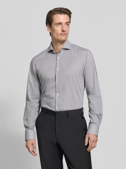 Męski model nosi Slim Fit Businesshemd aus reiner Baumwolle Modell 'HANK' von BOSS, jasnoszara koszula, ciemne spodnie, całopostaciowe ujęcie z przodu, koszule biznesowe