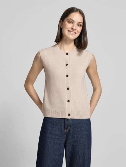 Frauenmodel trägt Regular Fit Strickweste aus reiner Schurwolle von Marc O'Polo in Beige mit dunklen Knöpfen, Ganzkörperansicht von vorne, Damen Strickweste von Marc O'Polo.